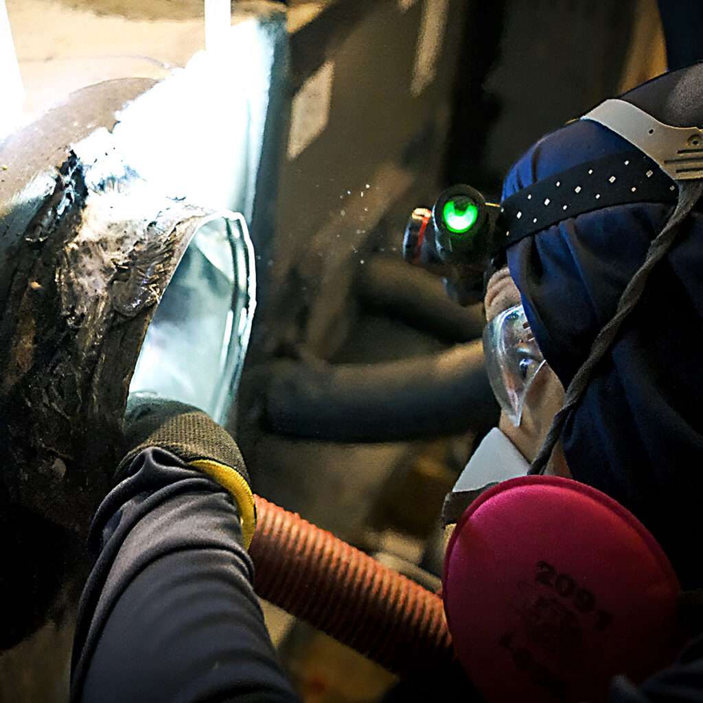 Air Quality Express technician in respirator cleaning mold from an air duct in Houston